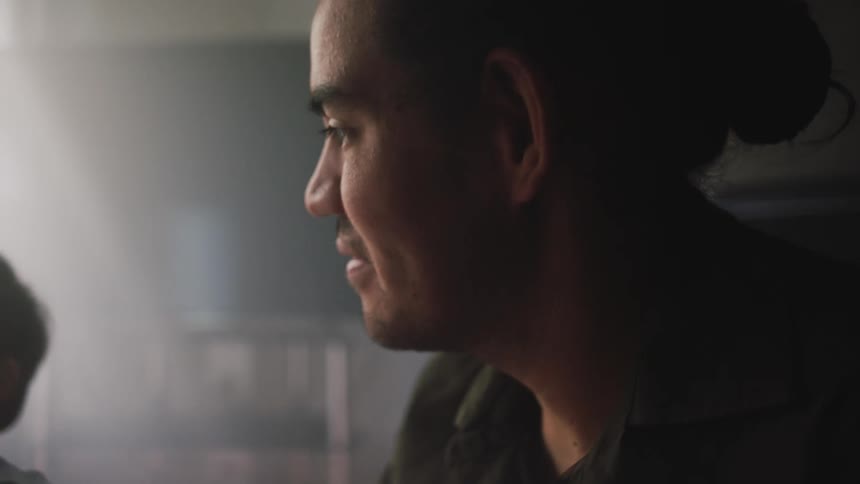 A close up of a mans face smiling while talking to someone and looking at his son