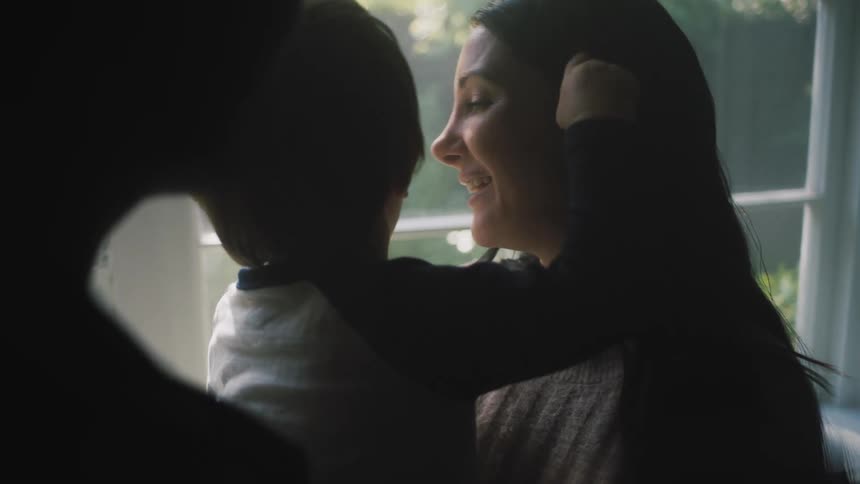 Father stands near mother holding their son who is sucking on a pacifier