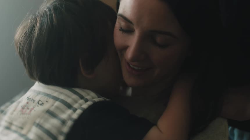 A woman is smiling as she holds her young son and hugs him