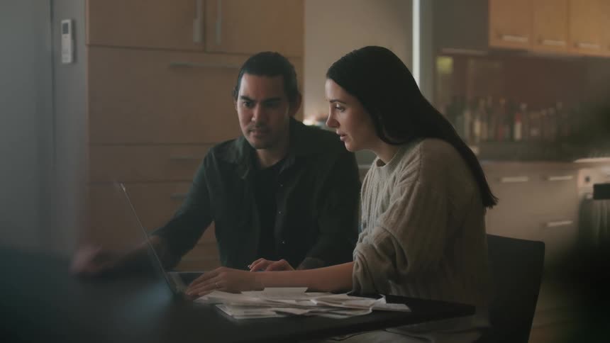 Two people are talking while looking at the laptop