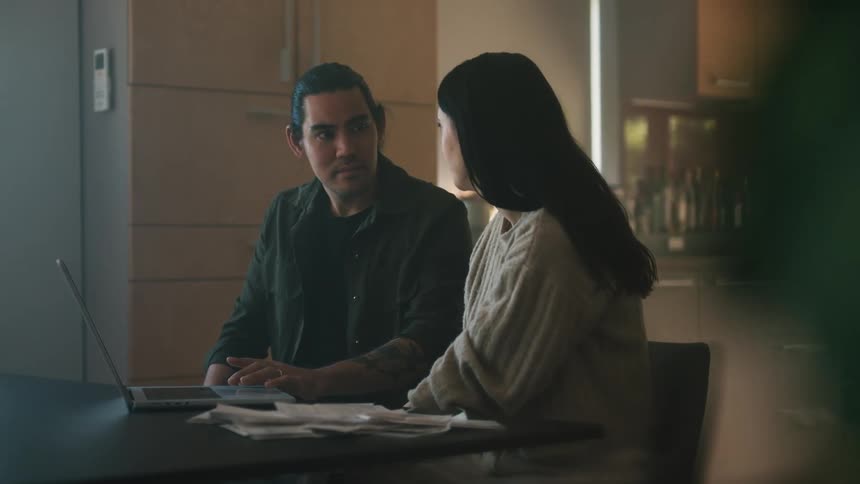 A man and woman talk while looking at a laptop