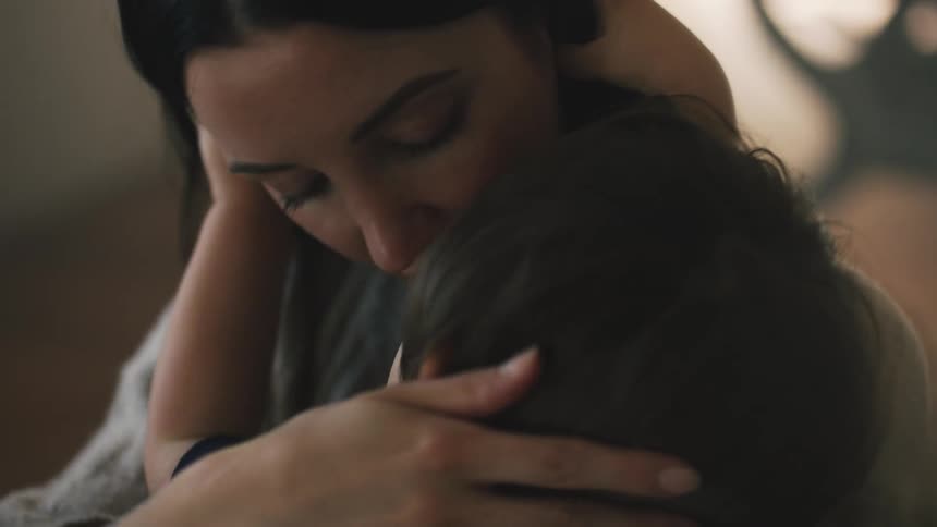 A woman holds her child close while kissing and caressing him