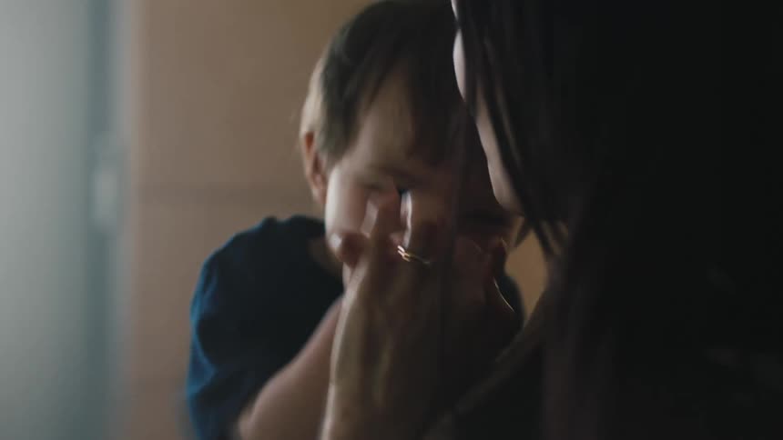 Mother smiles and playfully tickles son while holding him