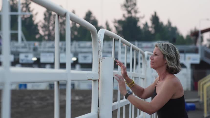 A woman climbs down the gate of the arena