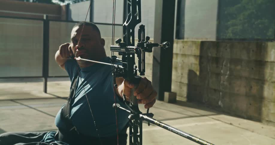 Man in a wheelchair practicing archery using a compound bow