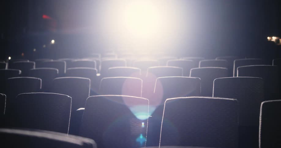 Several chairs in a theater with a bright light coming from the back
