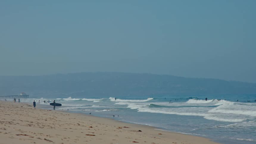 A person is holding a surfboard on the beach