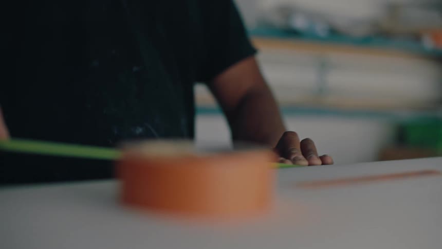 Person putting a green ribbon around a surfboard