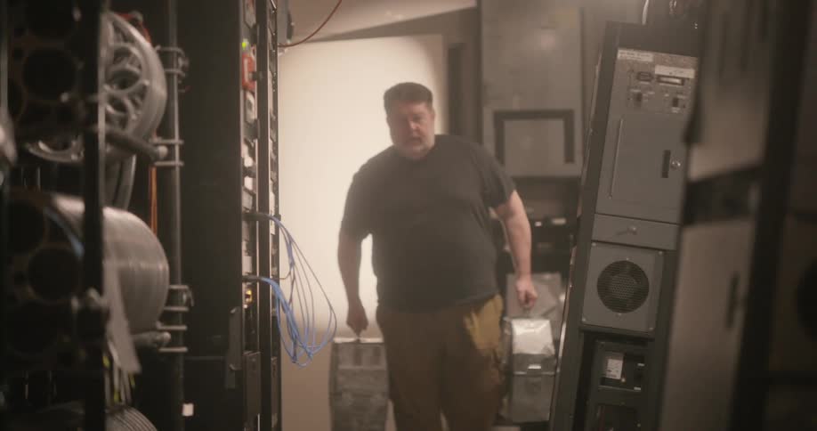 An adult man arriving in a room carrying two suitcases in his hands