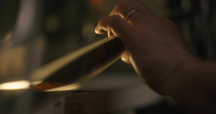 Projectionist manipulates a film strip in a dimly lit room