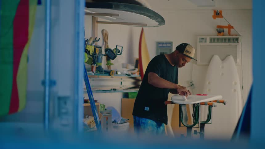 A man is working on a surfboard