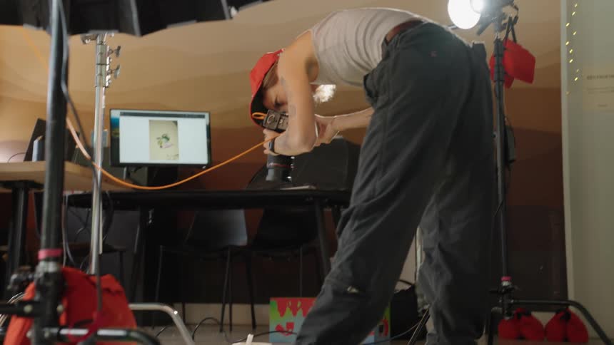 Photographer using a professional camera in a studio with objects on the floor