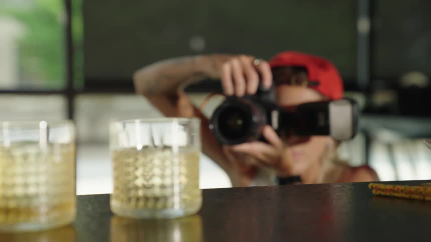 Professional photographer takes pictures of drinks on a counter while traffic passes on the street in the background