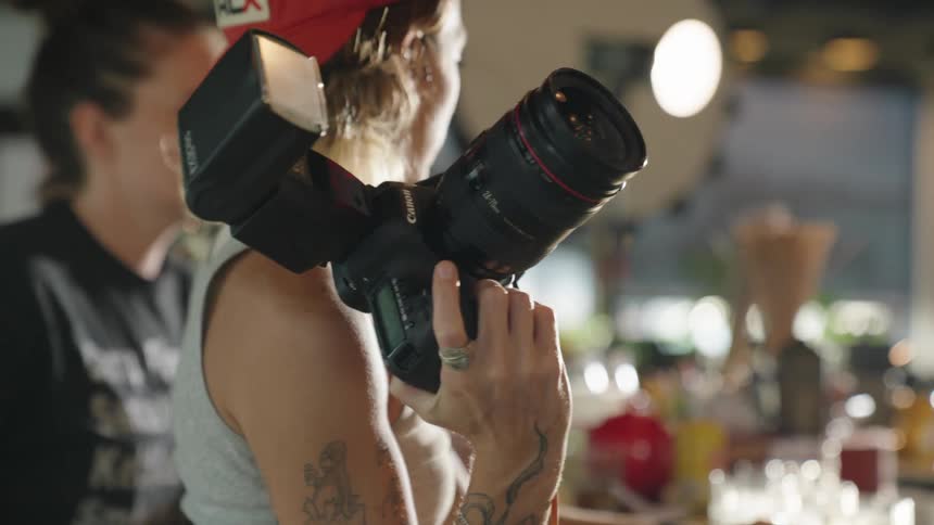 Female photographer holding a professional camera indoors
