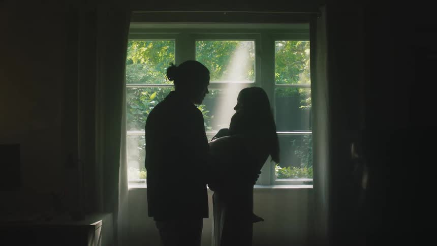A man consoles his wife and child in a living room