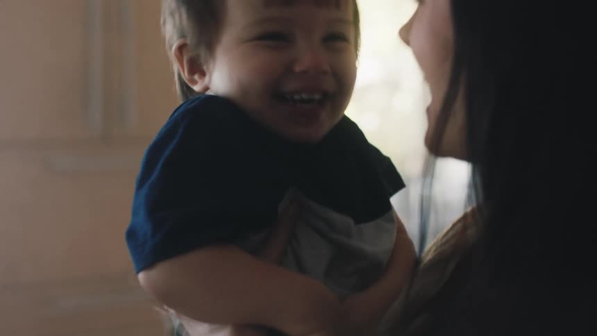 A joyful mother cradling her laughing son in her arms