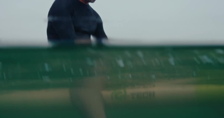 A man sits on his surfboard in the water going through items