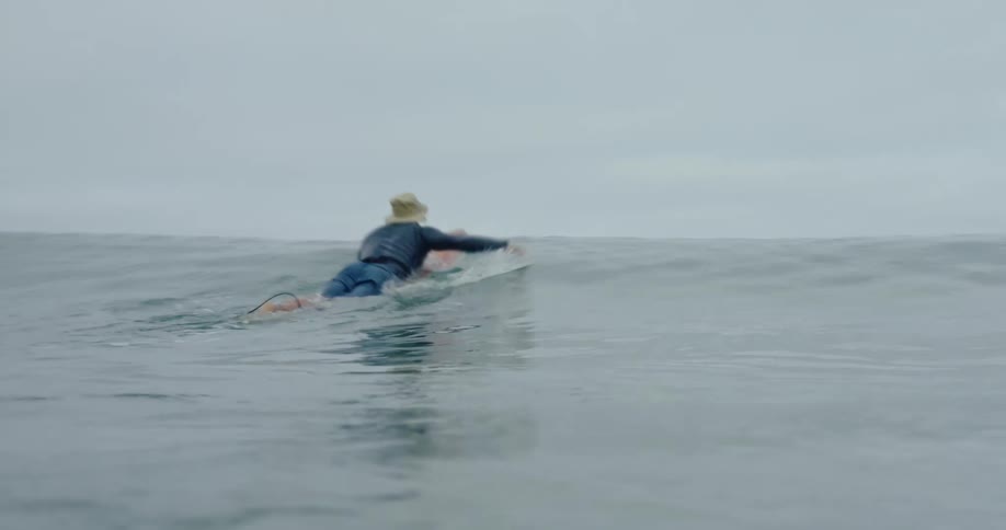 A person on a surfboard is surfing and riding a small wave
