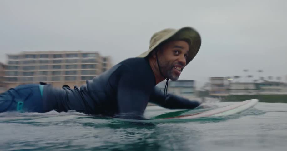 A man is paddling on his surfboard