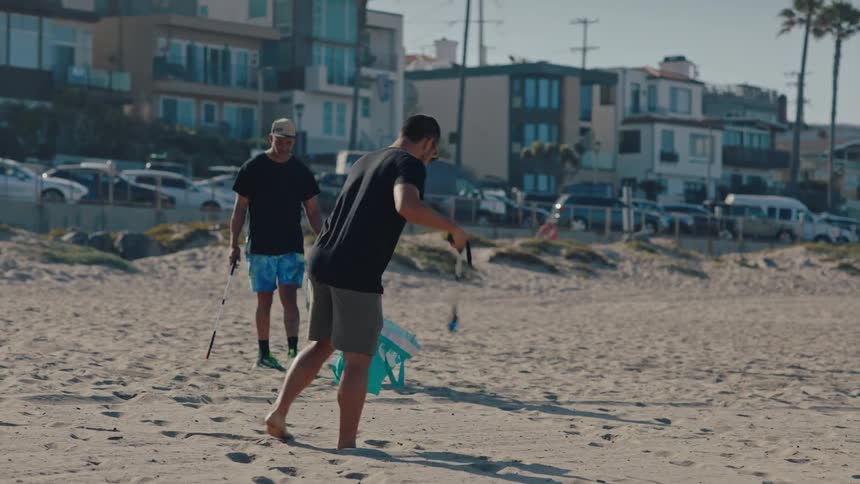 Two men pick up litter off of a beach