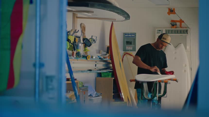 A man is polishing a surfboard