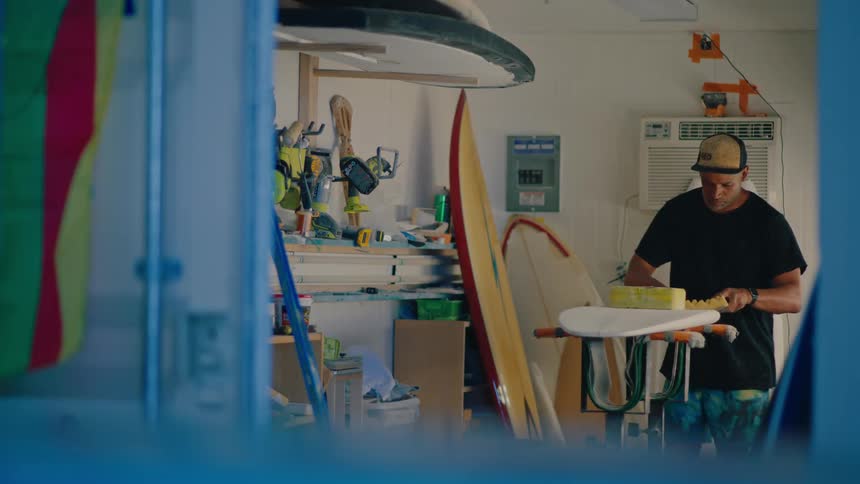 A man is sanding a surfboard