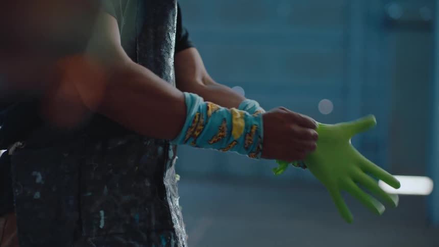 A person is putting green gloves on his hands