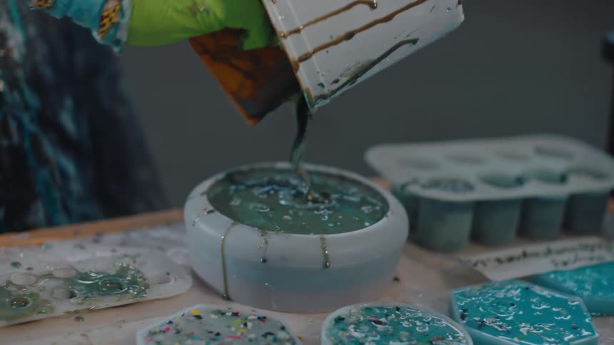Bucket pouring paint into small molds