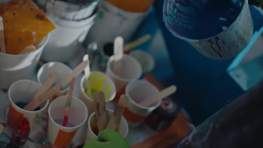 Bucket with water pouring into cups with paint