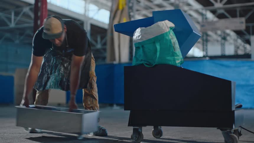 Man in apron picking up metal box
