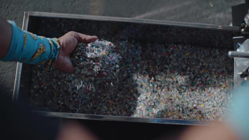 A person opening a metal drawer with several crushed microplastics inside