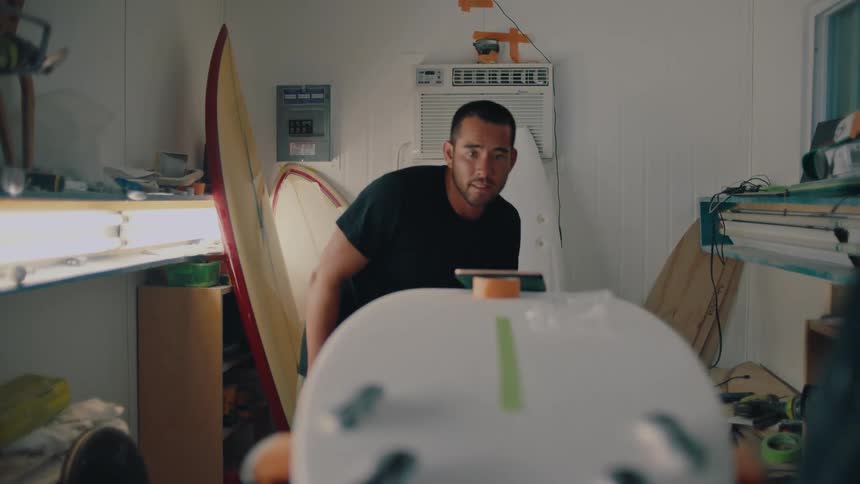 A man is preparing a surfboard