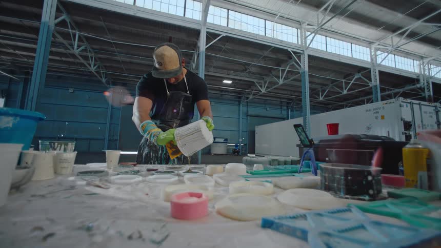 Man removing paint from a bucket and pouring it into small jars on a table