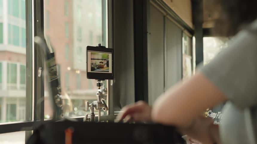 Womans arm using a laptop and next to it a screen displaying photos