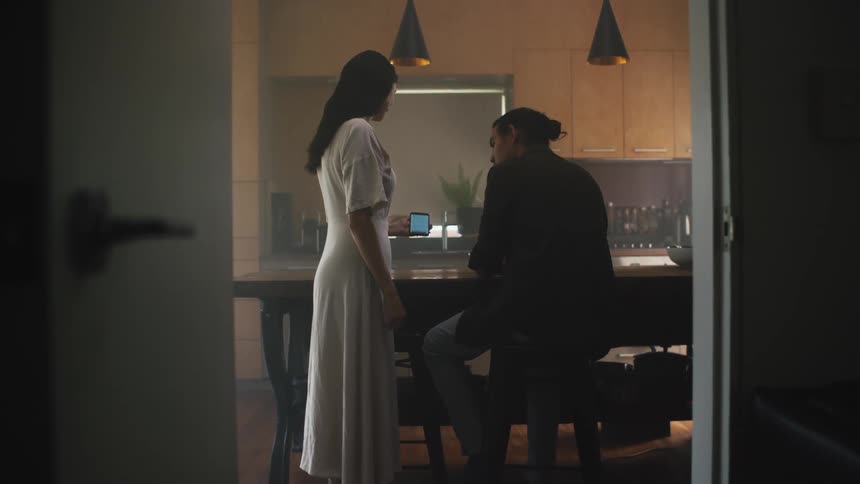 A woman walks over to a man with her cell phone