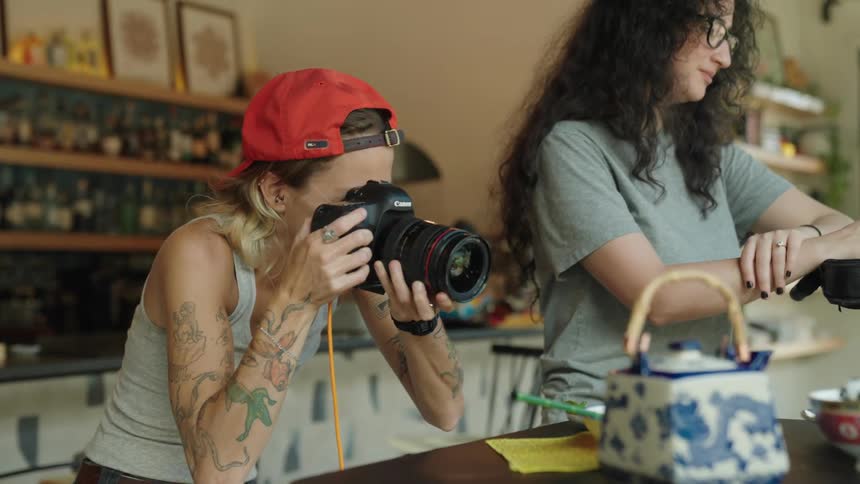 Woman with a professional camera photographing objects inside a store next to two other women