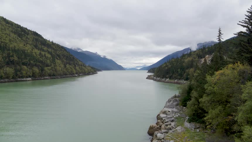 Glacial water flows in a deep channel surround by tree covered mountains