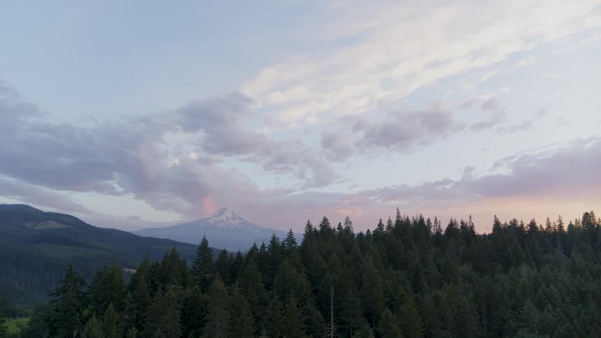 Tilt down reveal of snow capped Mount Hood beneath a painted sky