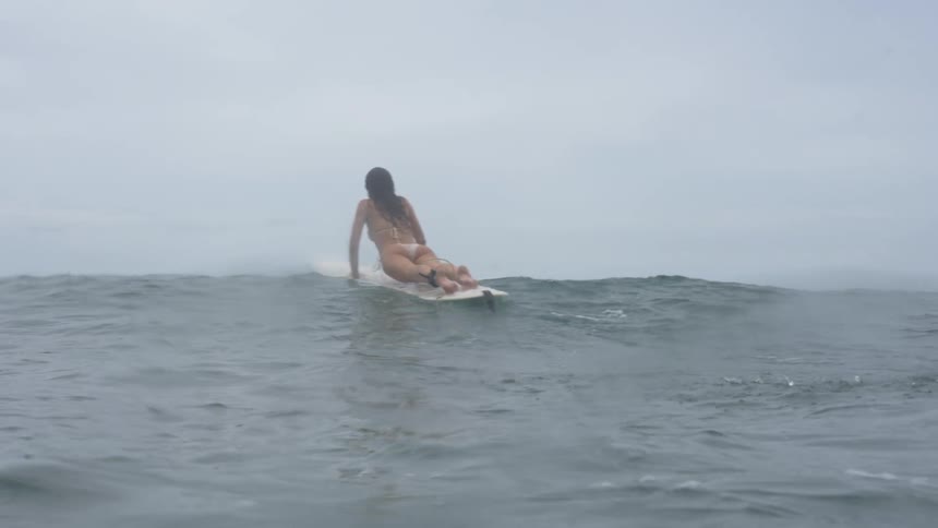 Woman on a surfboard riding a wave in the middle of the sea