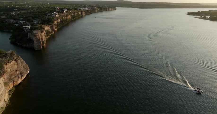 Aerial view of a sea canal with a boat passing through and the rocky coastline with houses