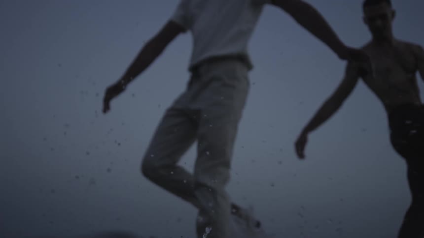 Two men walking in a circle through the water on a cloudy day