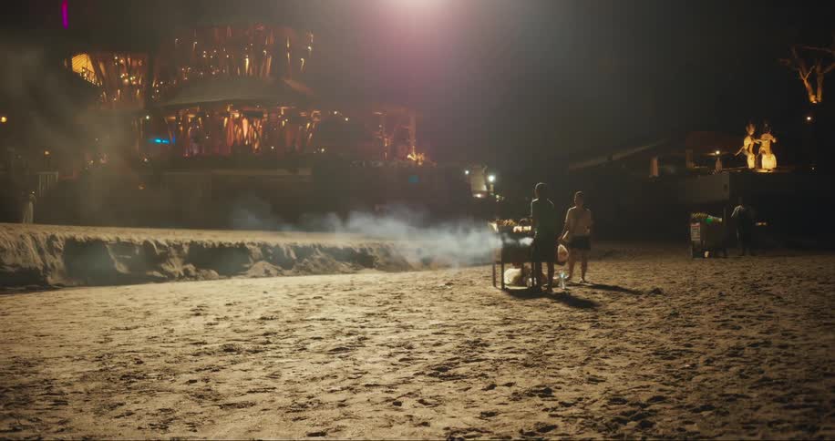 People are barbecuing on the beach at night