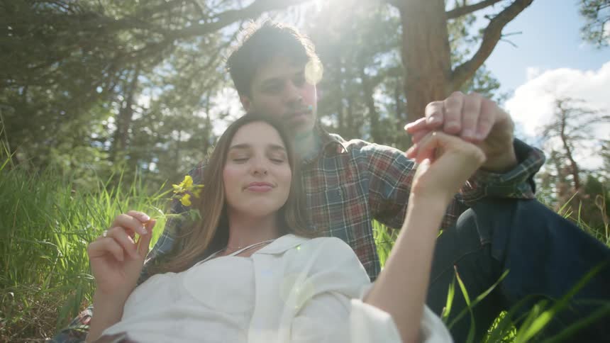 Couple sitting in a field with trees around in a romantic and happy way