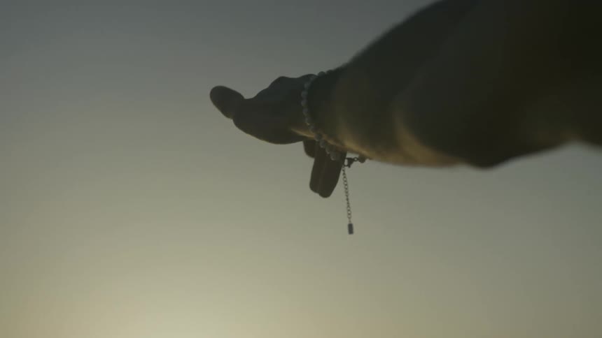 Man reaches toward the sky after dusk