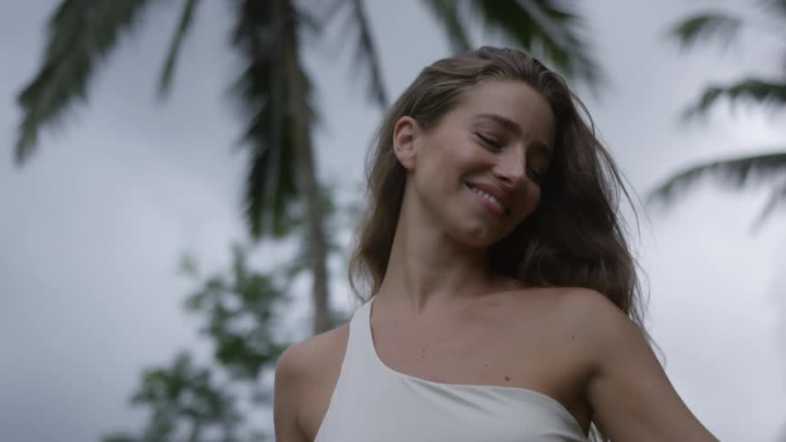 Woman smiling and walking in a tropical coconut tree environment