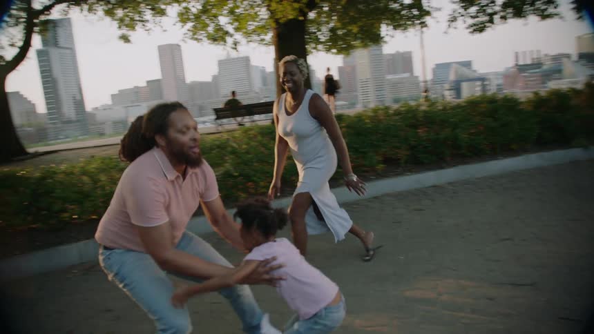 Little girl running straight into her fathers arms next to her mother in a square