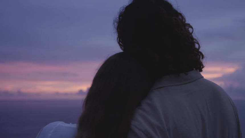 A couple hug as they watch the sunset