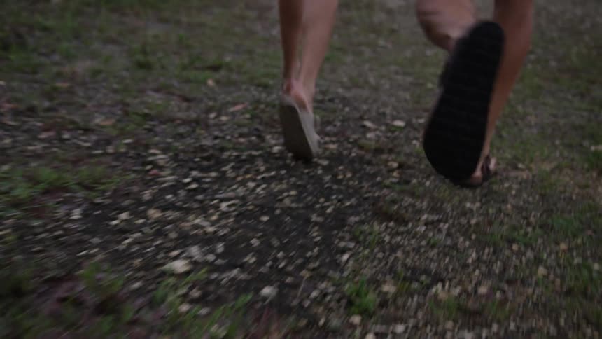 A couple running on a gravel path wearing sandals