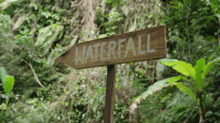 Wooden sign in the middle of nature signaling a waterfall