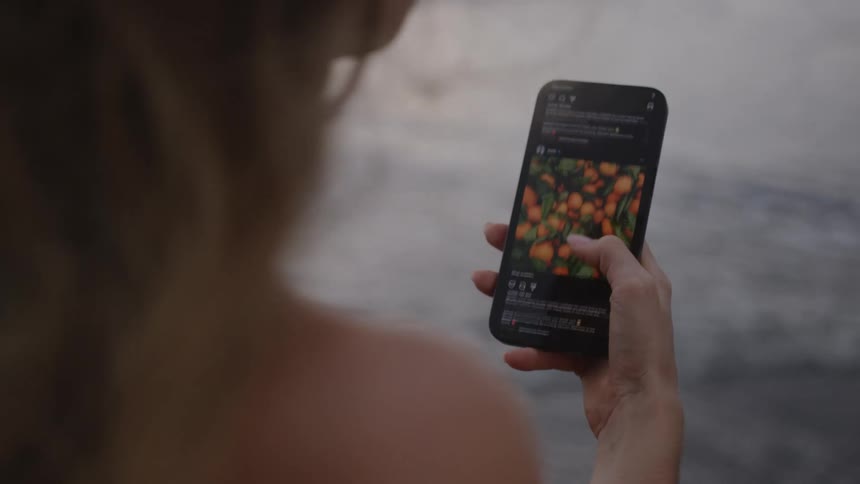 Woman scrolls on her smartphone while near flowing water